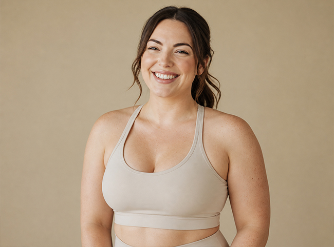 Smiling woman in neutral activewear against a warm beige background